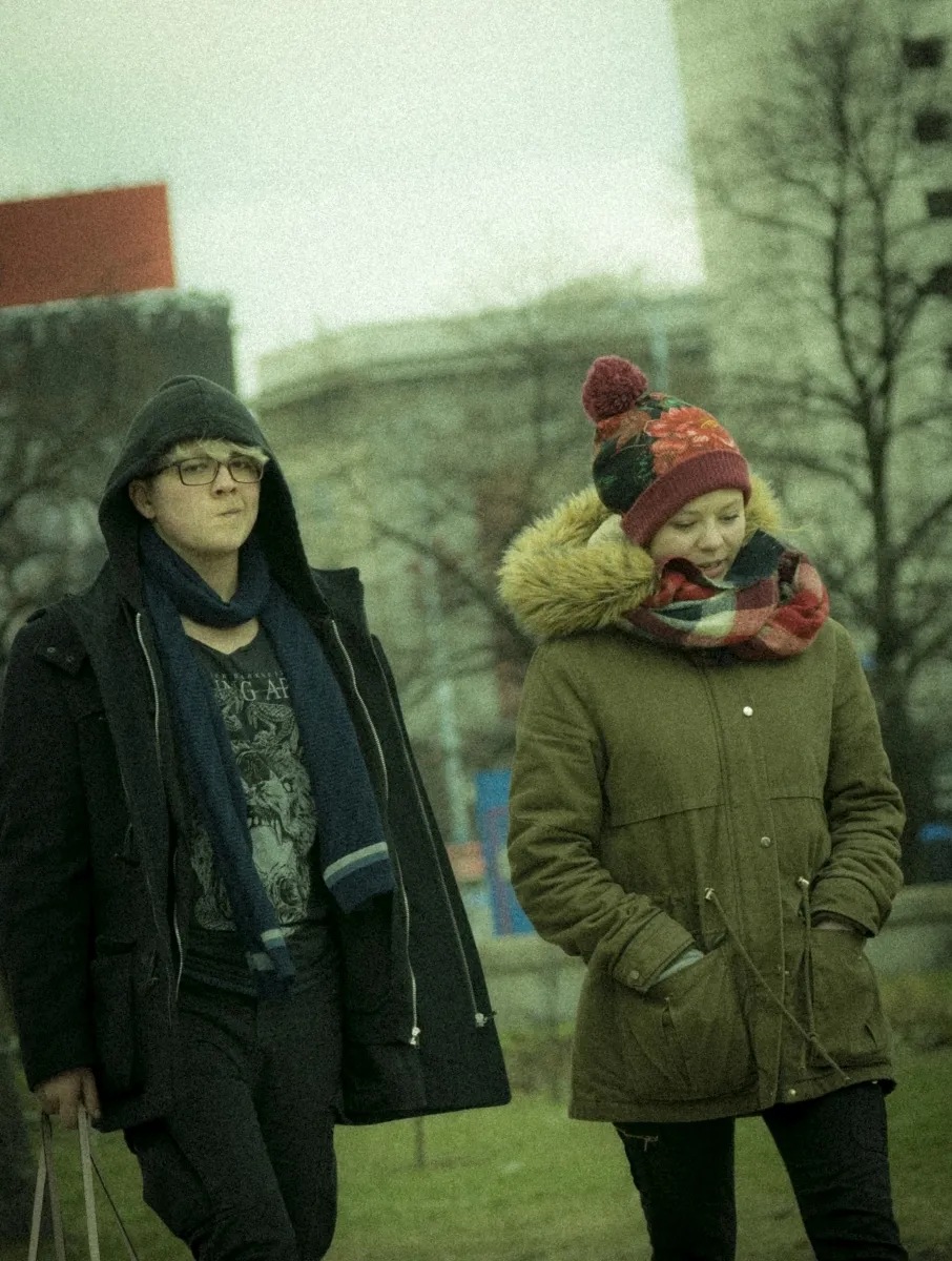 Two bundled pedestrians walking side by side in a winter park